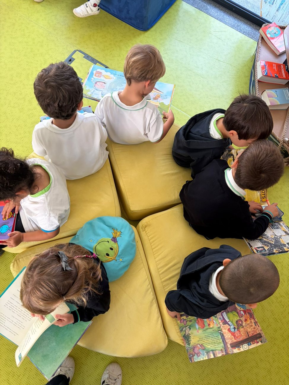 Crianças sentadas em almofadas amarelas a folhear livros