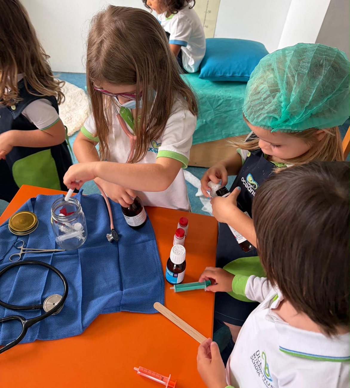 Crianças a brincar aos médicos numa mesa com material hospitalar de brincar