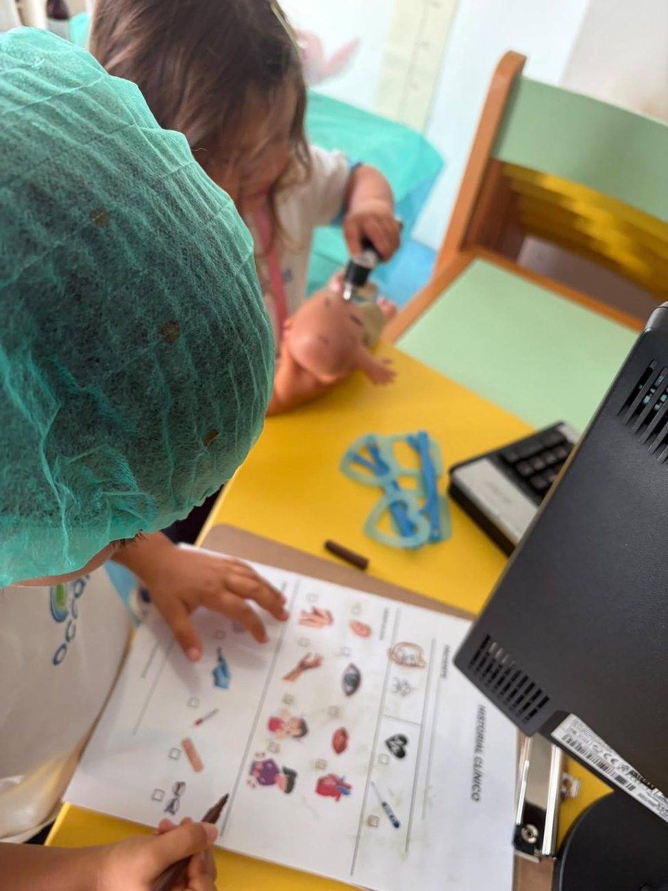 Criança com touca a brincar aos médicos com uma boneca