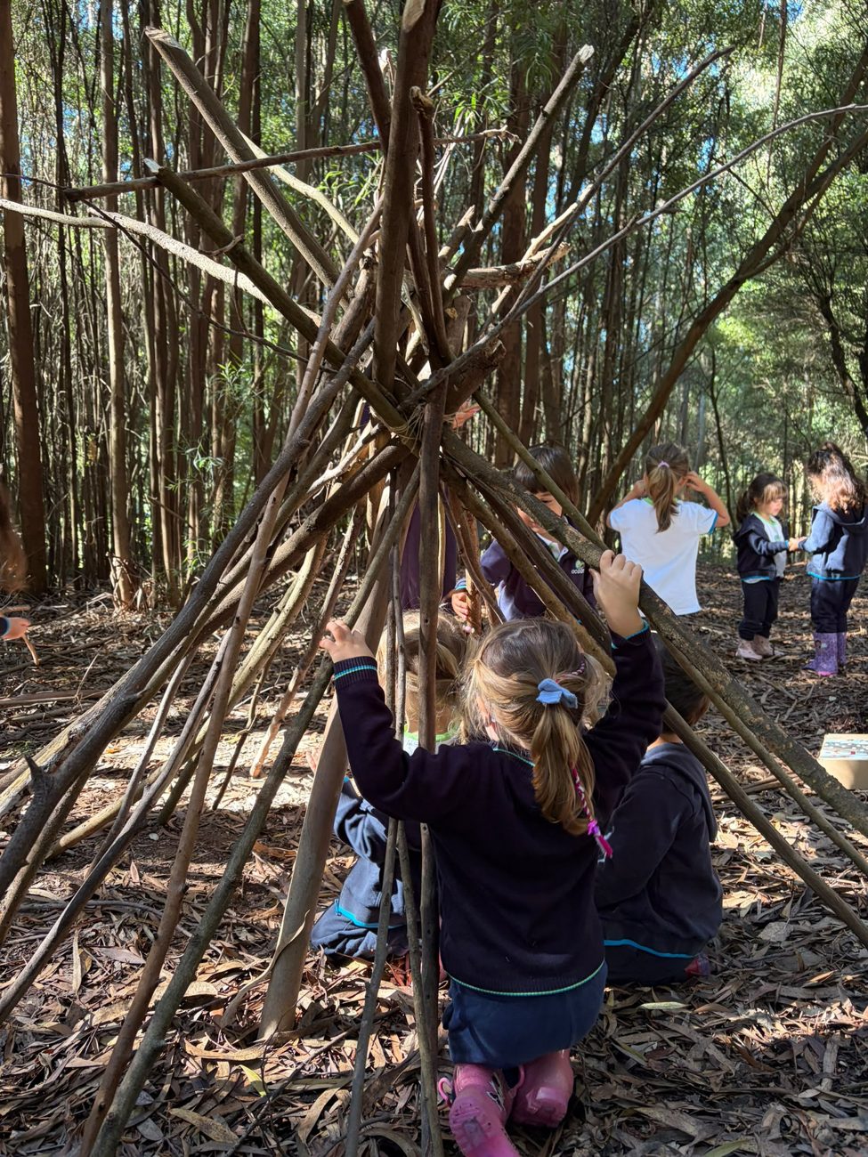 Crianças a brincar numa cabana de ramos na floresta